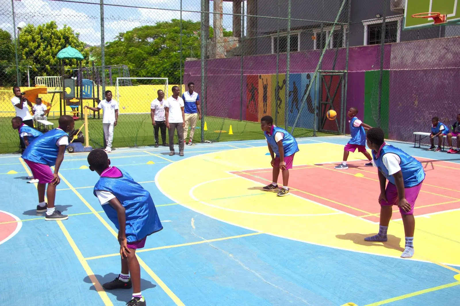 Pupils in blue sports kits playing basketball near the hoop