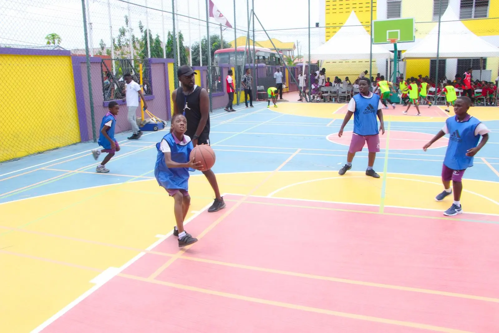 Pupils in blue sports kits dribbling basketballs on the HABIS court