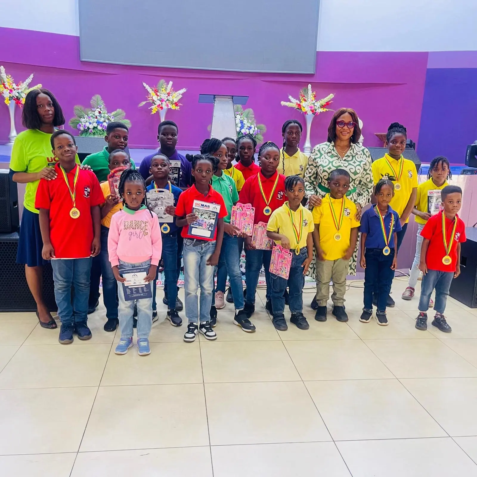 Children and adults in brightly coloured shirts posing together indoors