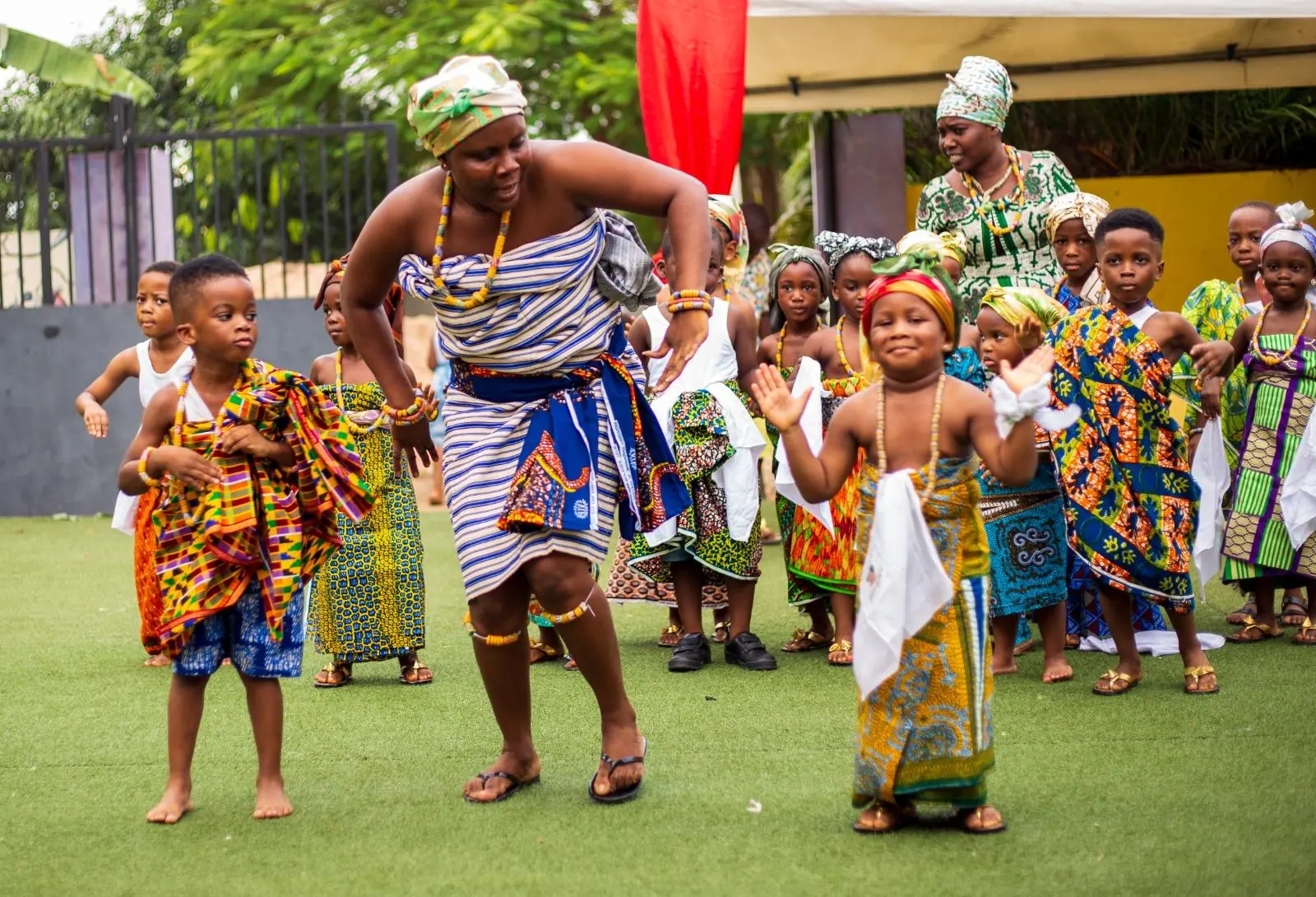 An adult dancing alongside young pupils in traditional clothing