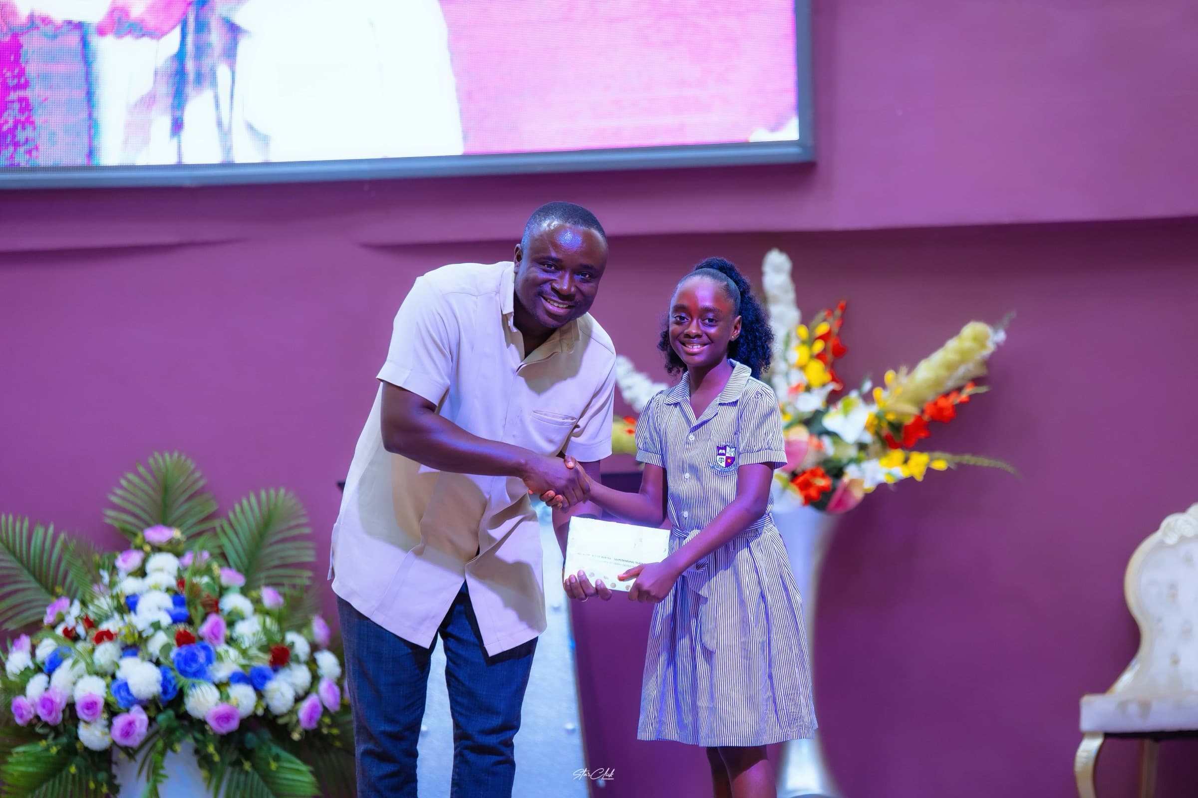 A smiling HABIS pupil receiving an achievement award