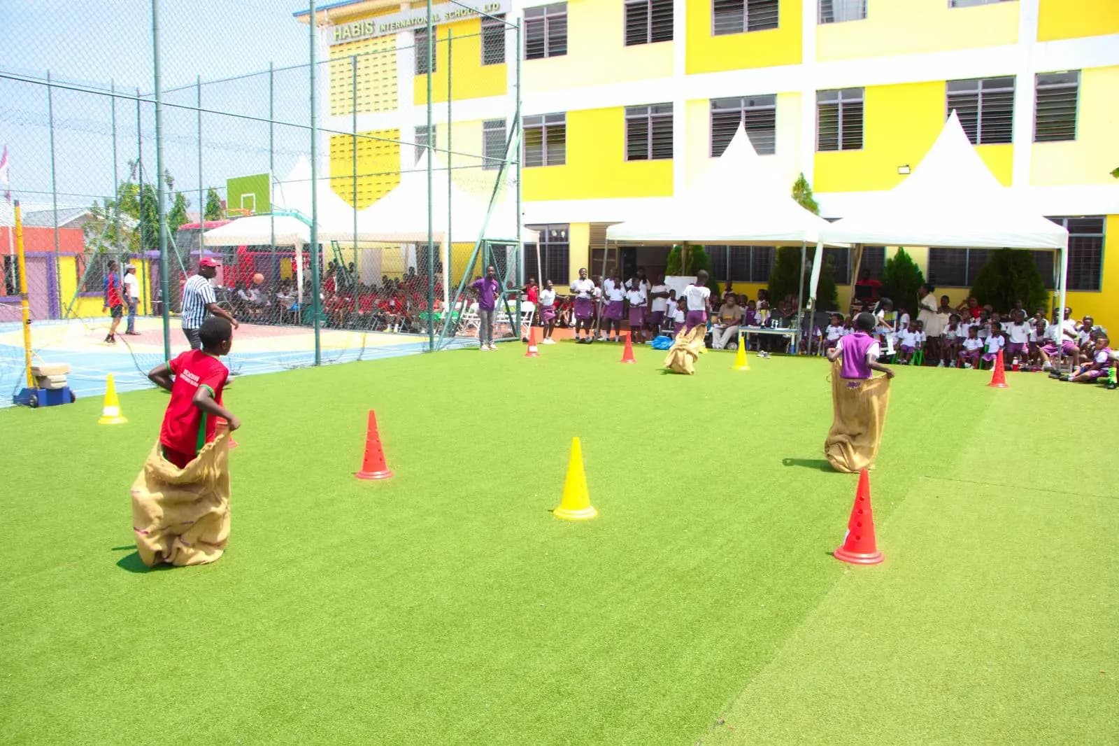 HABIS pupils competing in a sack race between cones on the school field