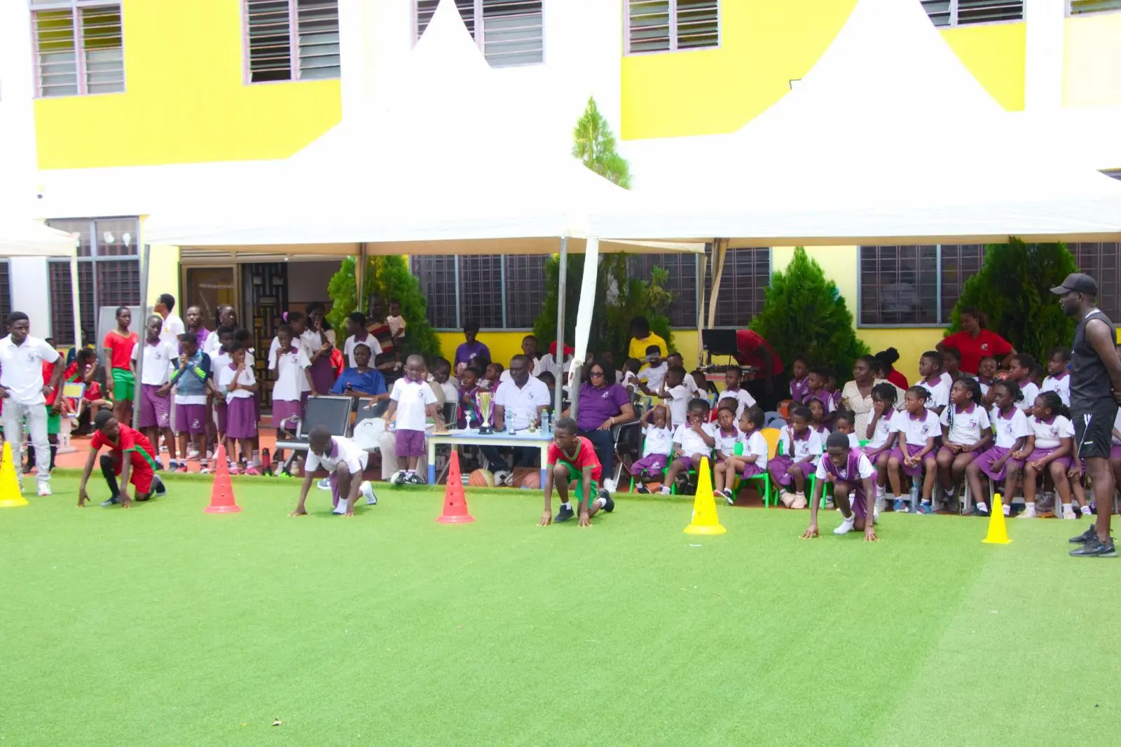 Pupils and families watching sports activities outside the HABIS school building