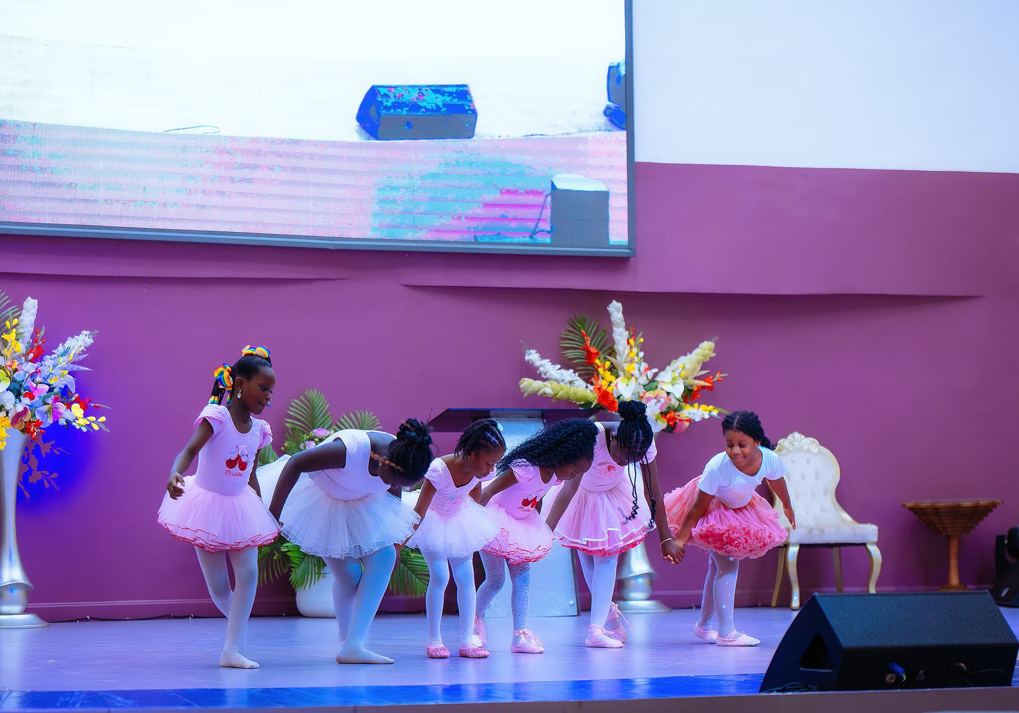 Young HABIS dancers in pink and white costumes taking a bow