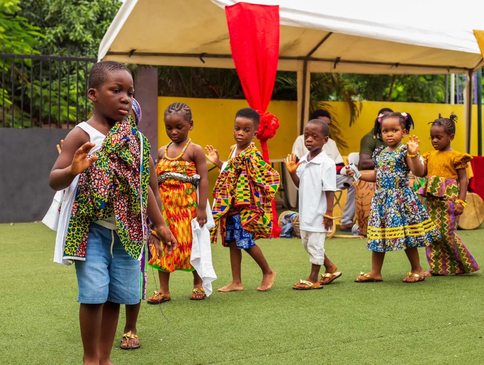 Young pupils in patterned traditional clothing performing on the HABIS field