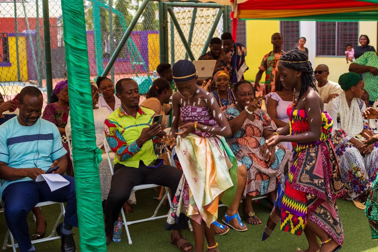 Young HABIS pupils performing in traditional dress beside seated spectators
