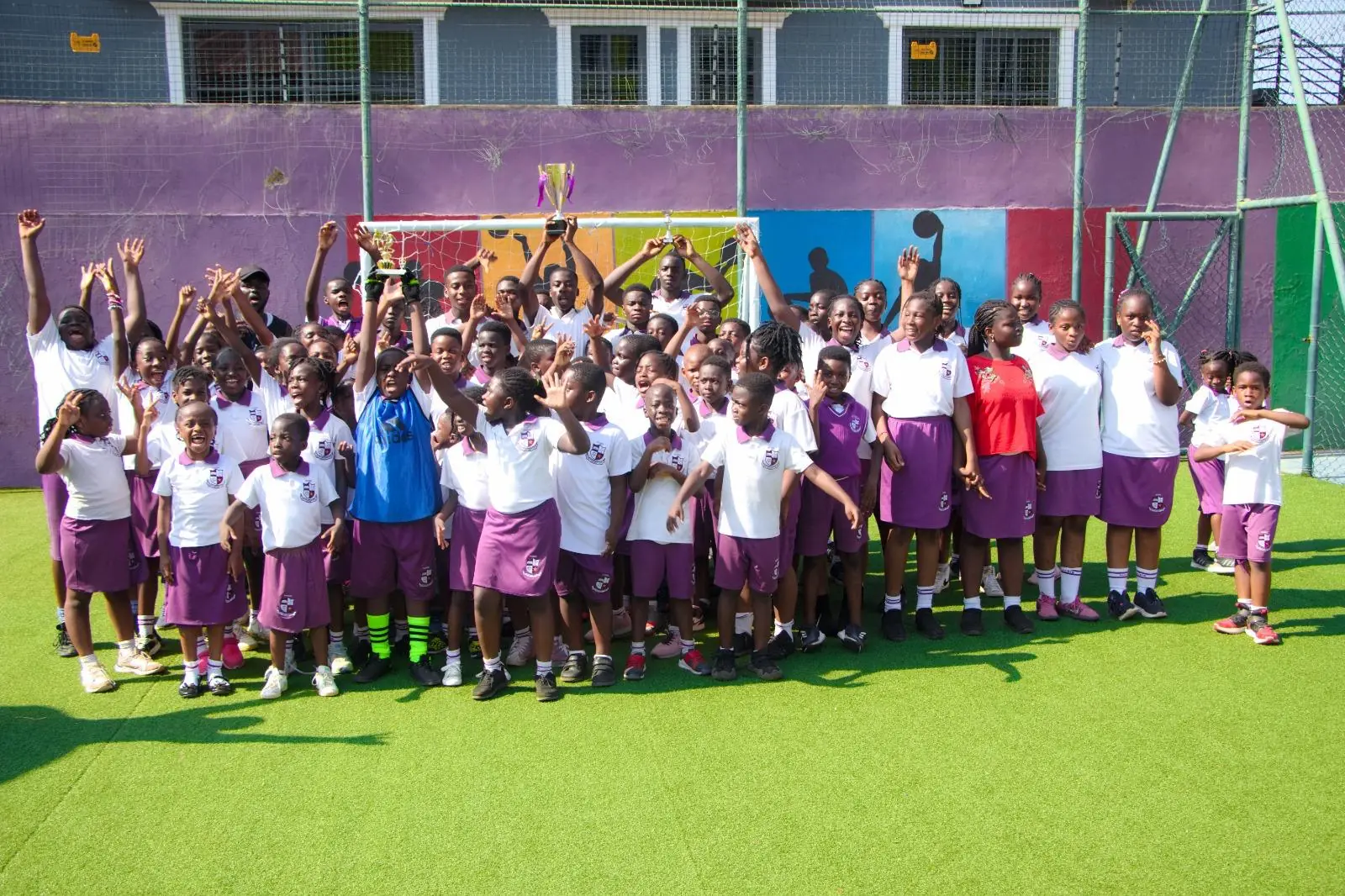 HABIS pupils smiling and raising their hands together on the school court